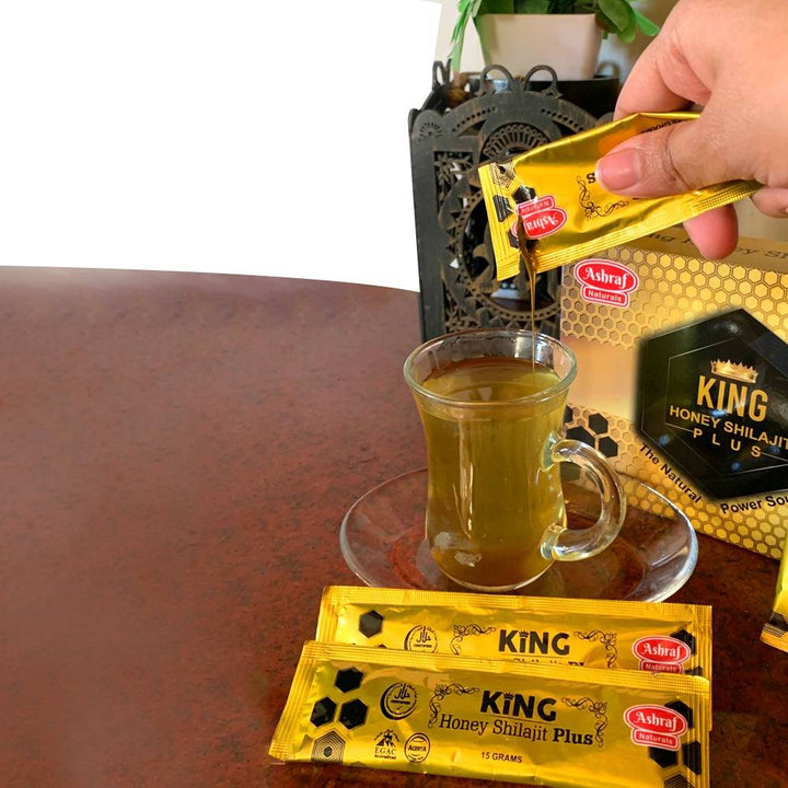 A person pouring tea into a cup with a packet of King Honey.